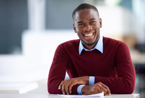 Young man sitting at a table smiling at the camera